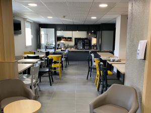 um restaurante com mesas e cadeiras e uma cozinha em B&B HOTEL Le Tréport Friville em Friville-Escarbotin
