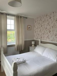 een slaapkamer met een wit bed en een raam bij Inn On The Wye in Ross on Wye