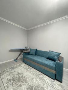 奇姆肯特的住宿－1-комн ЛЮКС в ЖК OTAU City，白色的房间里设有一张蓝色的沙发,配有桌子