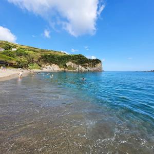 een groep mensen die op het strand in het water zwemmen bij Casa da Praia dos Moinhos in Ribeira Grande