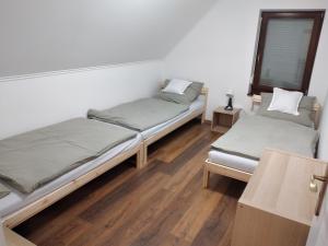 two beds in a room with wooden floors at Hamvas Vendégház in Tiszakécske