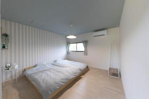 um pequeno quarto com uma cama e uma janela em guesthouse minkä em Amami