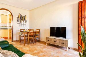 a living room with a television and a table with chairs at Bungalow Pink Torrevista in Torrevieja