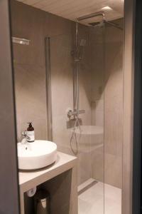 a bathroom with a sink and a glass shower at Seafront appartment Henningsvær in Henningsvær