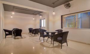 a dining room with chairs and tables and a clock at Treebo Trend De Alphabet Kondapur in Hyderabad