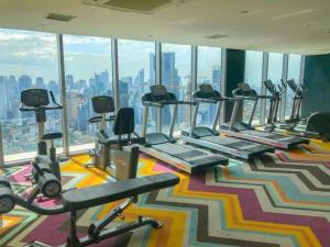 a gym with a row of treadmills and exercise bikes at Aveline Suites Cozy Skyline View ACQUA Private Residences near Rockwell Makati in Manila