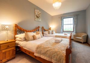 a bedroom with two beds and a chair at Aberhiriaeth Hall in Cemmaes