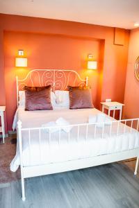 Cama blanca en habitación con pared de color naranja en Ancha Village, en Marbella
