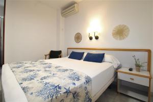 a bedroom with a bed with blue and white sheets at Hotel Canada in Benicàssim