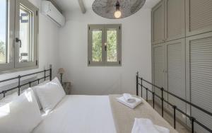 a white bedroom with a bed and two windows at Happy Babi in Adamantas