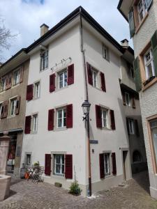 ein weißes Gebäude mit roten Fensterläden in der Unterkunft Ferienhaus Altstadt CH-Rheinfelden in Rheinfelden