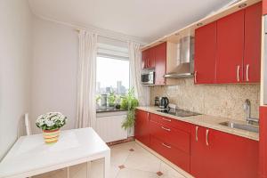 una cocina con armarios rojos y un jarrón de flores sobre una mesa en Vilnius view apartments (95 sqm), en Vilna