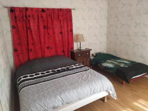 1 dormitorio con cama y cortina roja en Maison chaleureuse, en Saint-Jean-dʼAngély