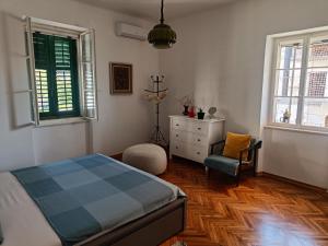 - une chambre avec un lit, une chaise et deux fenêtres dans l'établissement Nana's Place, à Tivat