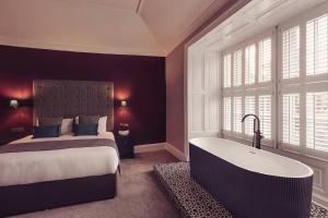 1 dormitorio con cama y bañera en Tweedies Bar and Lodge, en Grasmere