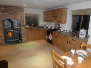 eine Küche mit Holzschränken, einem Tisch und einem Backofen in der Unterkunft Mile House Barn Bed & Breakfast in Nantwich