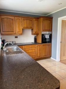 a kitchen with wooden cabinets and a granite counter top at ESNA, Stromness in Stromness