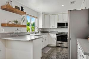 a kitchen with white cabinets and a refrigerator at City Terrace House only minutes From Down Town LA in Los Angeles