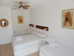 Dieses weiße Zimmer verfügt über 2 Betten und einen Deckenventilator. in der Unterkunft Liostasi Houses in Skyros