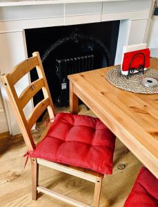 einen Holztisch mit einem Holzstuhl mit einem roten Kissen in der Unterkunft 1 bedroom apartment in Shepherds Bush, London in London