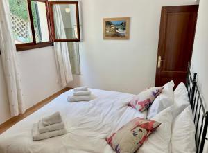 1 cama blanca con almohadas en el dormitorio en Beachhouse 2min to the sea with pool & wonderful garden, en Calviá