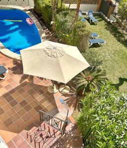 um guarda-sol e cadeiras junto a uma piscina em Beachhouse 2min to the sea with pool & wonderful garden em Calvià