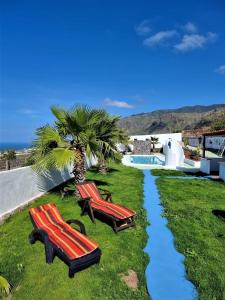 deux bancs rouges assis dans l'herbe à côté d'une piscine dans l'établissement Finca las Mariposas, à Los Silos