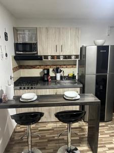 eine Küche mit einer Theke mit zwei Stühlen und einem Kühlschrank in der Unterkunft Apartamento central en Itagui in Itagüí