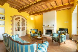 sala de estar con sillas azules y blancas y chimenea en Casale Stabbiatelli by VacaVilla, en Montenero