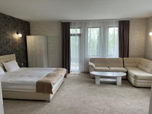 een slaapkamer met een bed, een bank en een tafel bij Chiflika Family Hotel in Asenovgrad