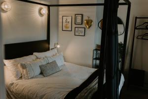 a bedroom with a canopy bed with white sheets and pillows at 37 Jubilee Street in Llandudno