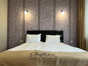 a bed with a hotel and restaurant sign on it at Chiflika Family Hotel in Asenovgrad