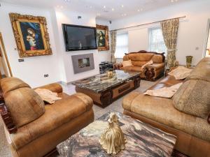 a living room with brown leather furniture and a flat screen tv at Bronte View Hideaway in Keighley