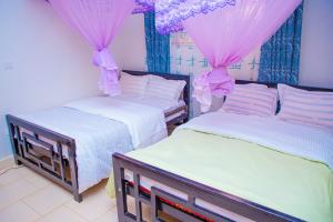 Mbale的住宿－J & A VILLAS，配有粉红色窗帘的客房内的两张床