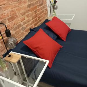 a blue bed with two red pillows on it at Hola Apartamenty Legionow 2 in Łódź