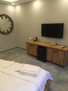 By Muhtar Hotel Bodrum في بودروم: غرفة بها ساعة كبيرة وتلفزيون