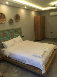 um quarto com uma cama grande e lençóis brancos em By Muhtar Hotel Bodrum em Bodrum City