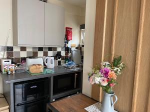 una cocina con un jarrón de flores sobre una mesa en Auntie Bett's - Cosy double ensuite room with mini kitchen en Kingsbridge