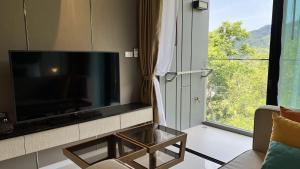a living room with a large flat screen tv next to a window at Panora Surin mountain view by EIE.ASSIA in Ban Lum Fuang