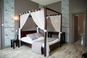 1 dormitorio con cama con dosel y cortinas en Logis Auberge De L'ombrée, en Combrée