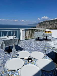 a table with white plates on a patio with the ocean at Hotel Klein Wien in Piano di Sorrento