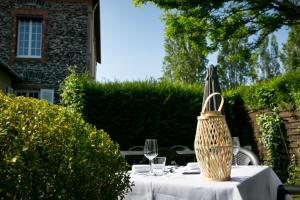 una mesa con copas de vino y una sombrilla. en Logis Auberge De L'ombrée en Combrée