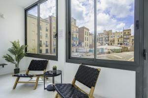 two chairs sitting in a room with windows at The White Flats Sant Antoni in Barcelona