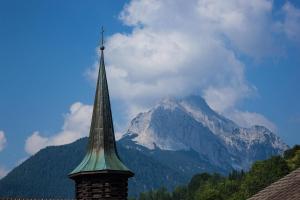 ein Kirchturm mit einem Berg im Hintergrund in der Unterkunft Ferienhaus Adelia in Mittenwald