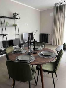 una mesa de madera con sillas, platos y copas de vino en Bierinu apartamenti, en Riga