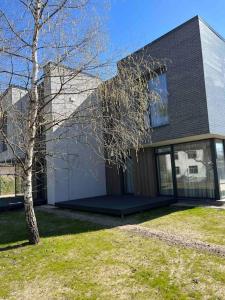 una casa con un árbol delante de ella en Bierinu apartamenti, en Riga