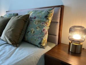 a bed with pillows and a lamp on a table at Bierinu apartamenti in Rīga