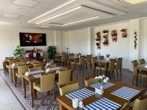 a restaurant with tables and chairs and a flat screen tv at Hotel Santana in Altınoluk