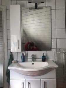 une personne prenant une photo d'un lavabo dans une salle de bains dans l'établissement Almenningsgata 9A, à Stavanger