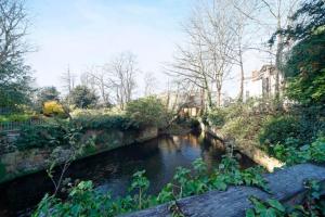 a river with a bridge in a park at Spacious comfortable & private parking in town centre in Cheltenham